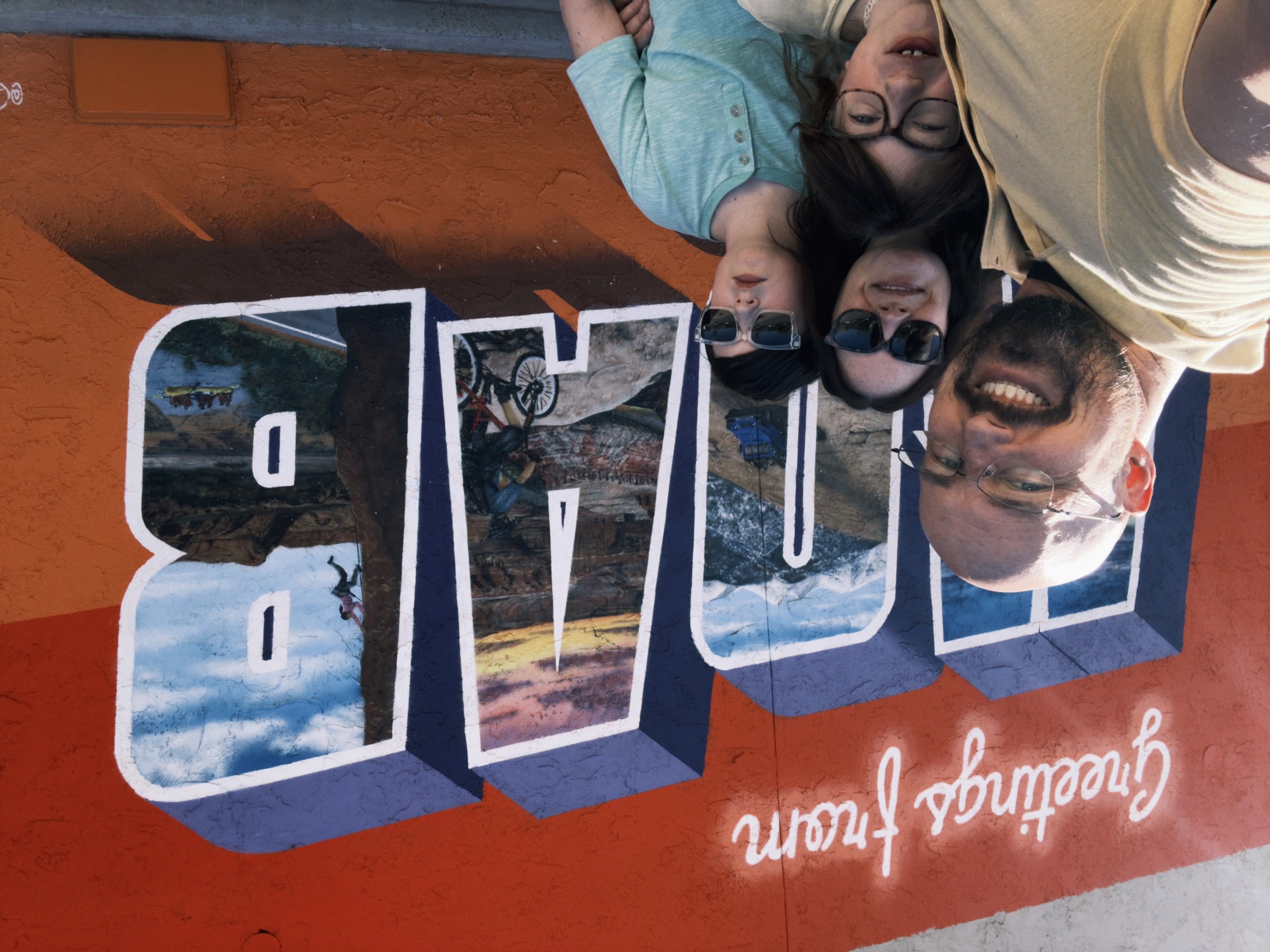 Family goofing around at a Greetings from Moab mural.